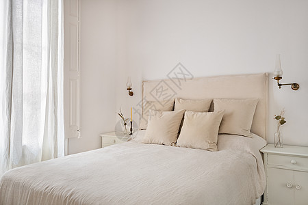 卧室内有明亮的卧室 睡着时带有枕头 米格麻布 旧灯和床边桌子上的干花图片