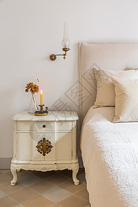 古老的卧室 有木制床边桌 在舒适的床上附近烧着蜡烛和鲜花 在旧式的温馨家庭内图片