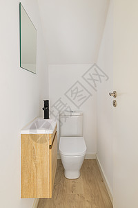 狭小的白色厕所 有小水槽 镜子和木制家具图片