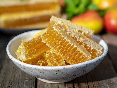 蜂巢中的蜂蜜 特写 在白色陶瓷板上 在木制质朴的桌子上 侧视图 阳光甜点营养强光木头草本植物食物金子液体水果陶瓷图片
