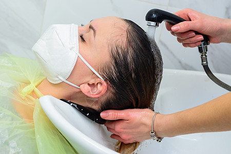 在世界隔离期间的发型师 在美容院洗头 一个戴面罩的客户蒙面人女性沙龙卫生治疗脸盆头发理发面具椅子图片
