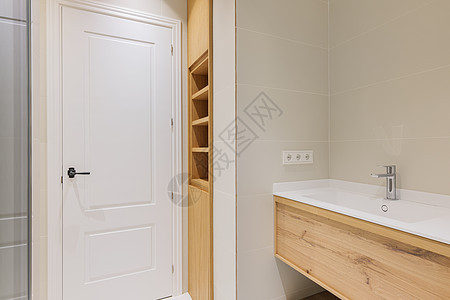 现代洗手间 有白色水槽的木质底座 装饰着轻瓷砖 内建带有架子的木制家具背景图片