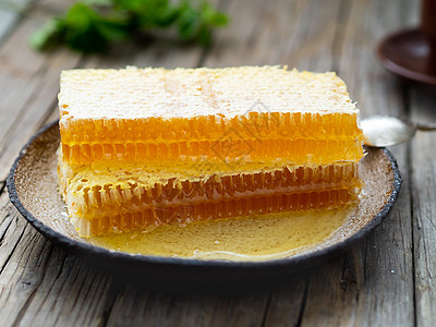 蜂蜜中的蜂蜜 特写 白色陶瓷板 木制生锈的桌子木头甜点食物金子美食液体药品蜂窝香料水果图片