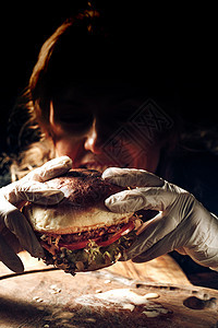 女孩用手套握着一个汉堡包背景图片