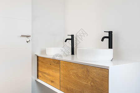 白瓦式洗手间有两个洗涤盆 黑色水龙头和木制柜子图片
