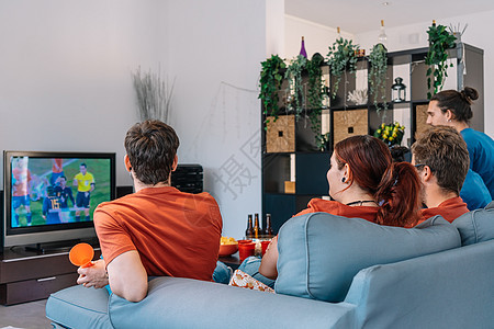 一群朋友在家里的沙发上放松 观看足球比赛 在电视上播放节目图片