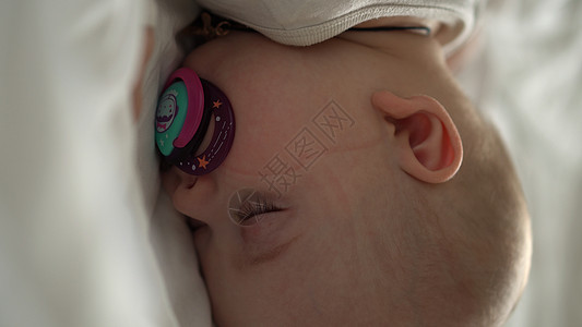 垂直特写脸新生儿胖乎乎的熟睡婴儿躺在肚子上睁开眼睛和微笑覆盖在床上的毯子在白色背景 婴儿期 儿童期 发育 医学和健康概念新生面罩图片