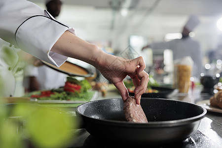 厨师亲近的手在热锅里煮牛肉饼 而烹饪美食饭作为晚餐服务图片