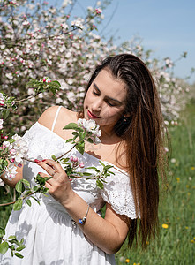 年轻的caucasian年轻女人 享受着苹果树的开花花园叶子植物群花朵女士幸福女孩黑发季节公园图片