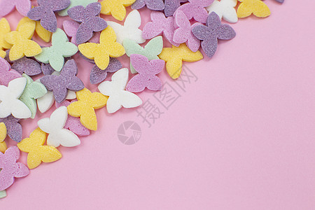 五颜六色的蝴蝶 一种流行的糖果浇头 斜躺在左角的粉红色背景上图片