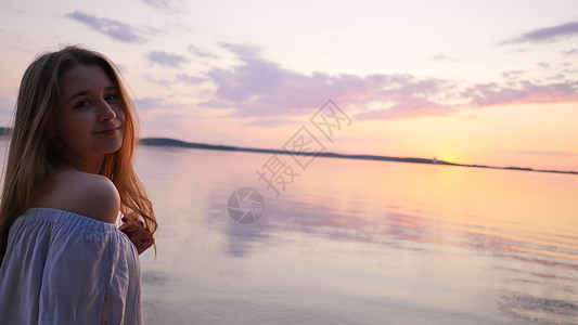 年轻女孩在海面和日落的背景身体橙子女士海洋海浪太阳青年海岸天空女性图片