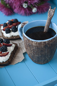 甜奶酪和浆果三明治 蓝木本底一杯咖啡的咖啡减肥食物饮食托盘面包早餐花束勺子杯子桌子图片