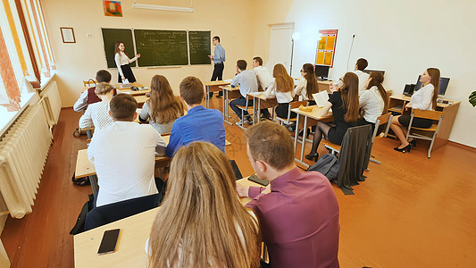 老师与学生教室里的学生在他们的书桌上 俄罗斯学校多样性平板瞳孔桌子头脑团体电脑教育大学微笑背景