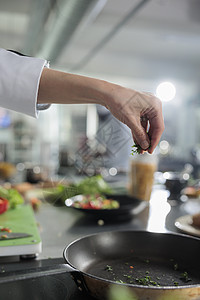 烹饪专家亲近的手 在餐厅厨房里用切开的新鲜草药 来制备美食菜图片