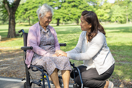 看护者帮助和照顾亚洲老年或老年老妇人病人坐在公园的轮椅上 快乐地坐在轮椅上 健康强大的医疗理念挑战药品照顾者退休诊所车轮疾病机动图片