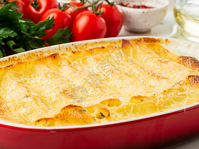 Cannelloni 填满了Ricotta和Parsley 烘烤的有b 沙梅酱 侧观 白大理石背景红色白色蔬菜午餐盘子菜单奶油桌图片