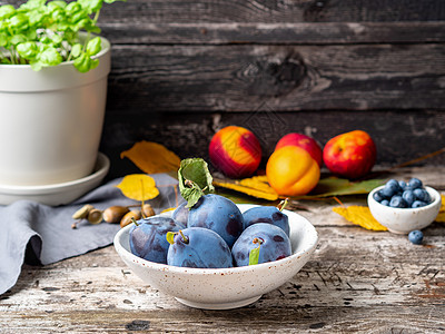 秋天背景 白碗中的紫紫色蓝色羽子成熟 旧灰色木制桌边的白碗农业水果情绪叶子团体艺术植物食物花园浆果图片