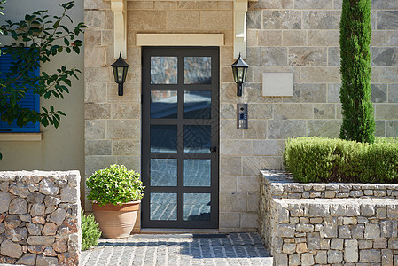 现代房屋外墙有石块 玻璃门和欧洲的灌木丛图片