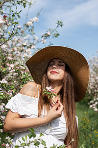 年轻的caucasian年轻女人 享受着苹果树的开花女孩植物群香气公园花园黑发叶子女士季节花朵图片