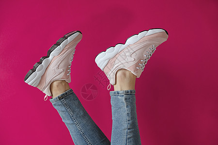 女人的脚穿着无名现代运动鞋 在粉红色背景上图片