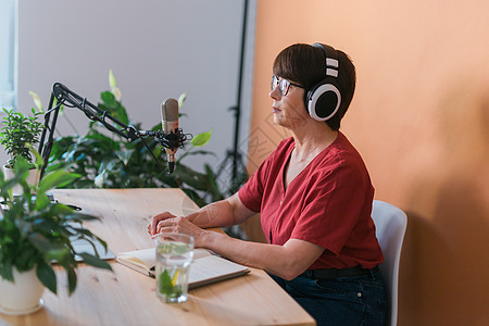 中年女电台主持人对着麦克风讲话和阅读新闻  电台广播在线概念居住扬声器工作室打碟机技术博主记者播客托管音乐图片