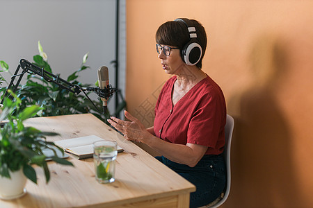 中年女电台主持人对着麦克风讲话和阅读新闻  电台广播在线概念记录托管女士打碟机生产扬声器收音机耳机音乐技术图片