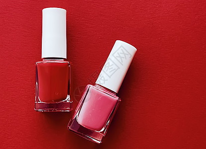 红底 修指甲和美容化妆品上的红色和粉红色指甲油瓶粉色玻璃美甲沙龙平铺抛光玫瑰瓶子背景图片