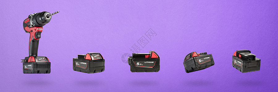 黑色和红色无绳电钻 紫色背景上带有钻头的螺丝刀和一组不同角度的电池 现代木工无绳工具特写图片