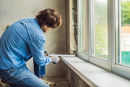 穿蓝衬衫的男人安装窗户的装置建设者体力劳动者玻璃工人建筑学房子建造维修塑料窗格图片