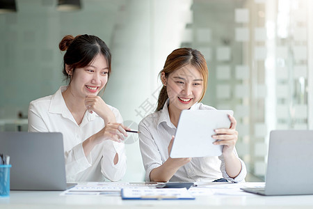 两位年轻的亚洲女商务人士讨论投资项目工作和规划战略 商界人士在办公室与笔记本电脑交谈伙伴推介会男性金融女士女性文书数据职员咨询图片