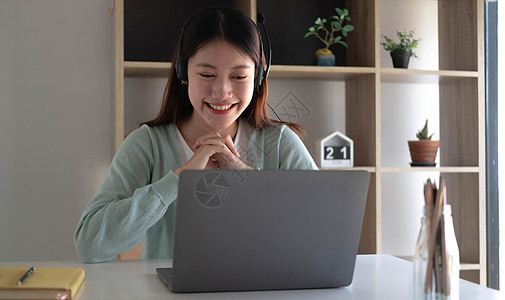 聪明的亚洲学生在互联网上在线学习和与朋友会面以在家中的笔记本电脑上搜索信息时会感到满足图片