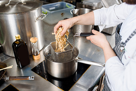 面条放在厨房的锅里 厨师为拉面汤煮意大利面条 用肉 蘑菇 萝卜 鸡蛋煮拉面汤图片