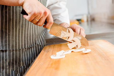 在厨房里切白蘑菇做拉面汤 厨师在餐厅用刀烹制白蘑菇 切白蘑菇图片