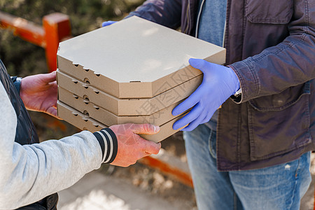 安全食品配送 戴着医用手套的快递员 顾客要拿 4 盒披萨 推广 2+2 披萨外卖 呆在家里图片