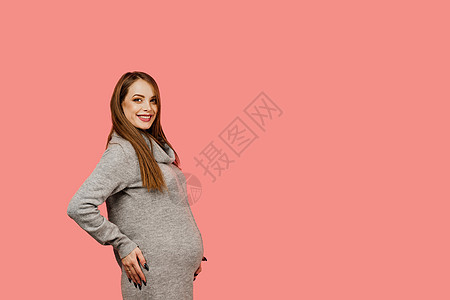 怀孕的女人 孩子的期望 产假 粉红色背景中身穿灰色毛衣的快乐美女怀孕父母分娩女士微笑福利腹部肚子婴儿粉色母性图片