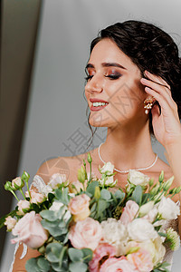 拿着婚礼花束的新娘微笑着抚摸着她的脸和头发 社交网络的迷人女孩肖像 在空白背景上穿着婚纱的女孩裙子婚姻魅力成人庆典奢华订婚花朵仪图片