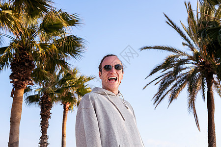 带着太阳眼镜的年轻天主教男子 快乐地欢笑着图片