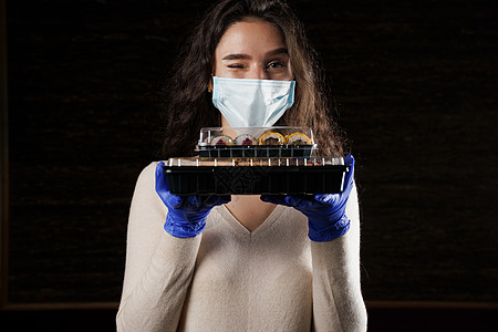 有寿司的女孩 戴着医用面具的食品快递员 在检疫冠状病毒 covid19 交付 年轻女子戴着手套手里拿着 2 个寿司盒导游美食大豆图片