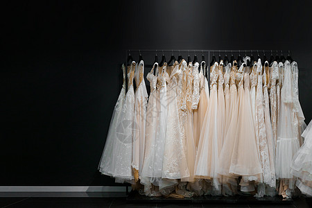 由真丝雪纺 薄纱和蕾丝制成的婚纱 美丽的白色奶油色新娘礼服挂在婚礼沙龙的衣架上 广告文字左侧空白的照片图片