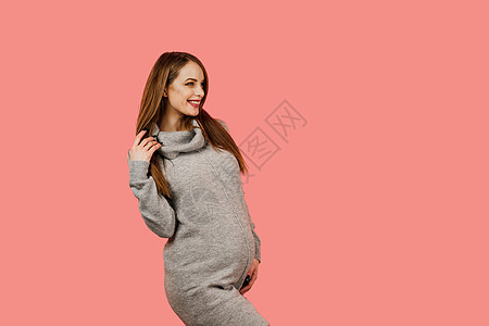怀孕的女人 孩子的期望 产假 粉红色背景中身穿灰色毛衣的快乐美女怀孕微笑分娩母亲父母母性粉色婴儿女孩福利女性图片