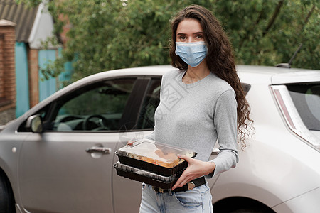 配有2个寿司盒的女信使戴医疗面具 站在车前站立着两个寿司箱感染防御海鲜手套导游外卖寿司消毒食物酱油图片