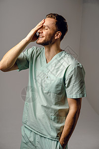 外科医生穿着医学长袍 微笑着笑容 假扮白色背景 在演播室里出现英俊的快乐医生保健卫生操作医院房间医师职业男人男性工人图片