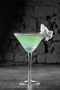 绿色酒精鸡尾酒在一个玻璃杯里装饰 用棉花糖在灰色背景上液体君度庆典玻璃餐厅果汁调酒师酒吧糖果补品图片