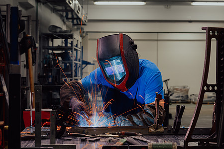 在工厂内工作的专业重工业焊工 戴着头盔并开始焊接 选择性焦点手套火花职场操作员机器制造业面具焊机闪光金工图片