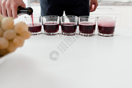 酒箱将红酒倒在白桌上的杯子上 红自制酒杯图片