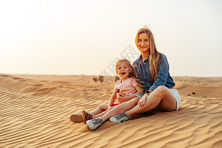 母亲和女儿一起坐在迪拜沙漠的沙丘上 坐在一起女士冒充游客女性姐妹孩子旅游旅行家庭冒险图片