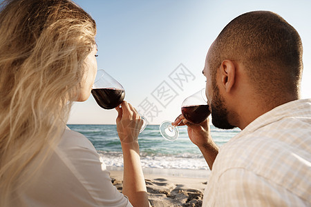 坐在海滩上喝着酒的一对年轻夫妇的肖像女性成人女士衣服乐趣男人妻子海滨玻璃海岸图片