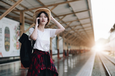 寻找朋友计划在火车站旅行的年轻旅行者妇女 夏天和旅行生活方式概念电话上网窗户帽子互联网火车技术细胞商业女孩图片