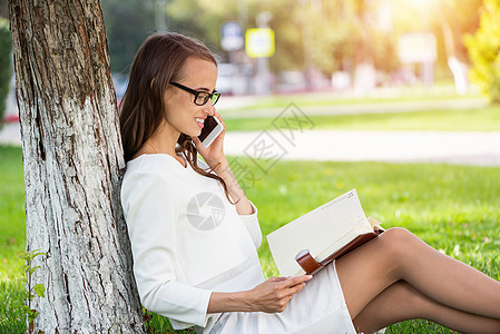 在公园里用电话打电话的女人细胞手机森林女性绿色商业微笑快乐技术成人图片