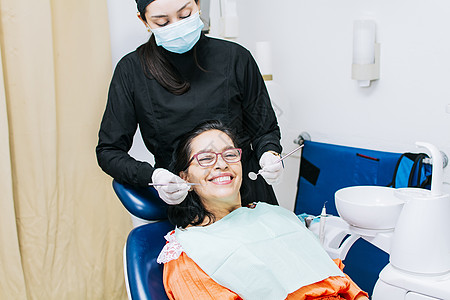 牙医为微笑的病人检查口腔 女牙医为女病人做根管治疗 女牙医和说谎的病人 牙医进行口腔科程序健康咨询手术诊所卫生牙科打扫口罩设备图片